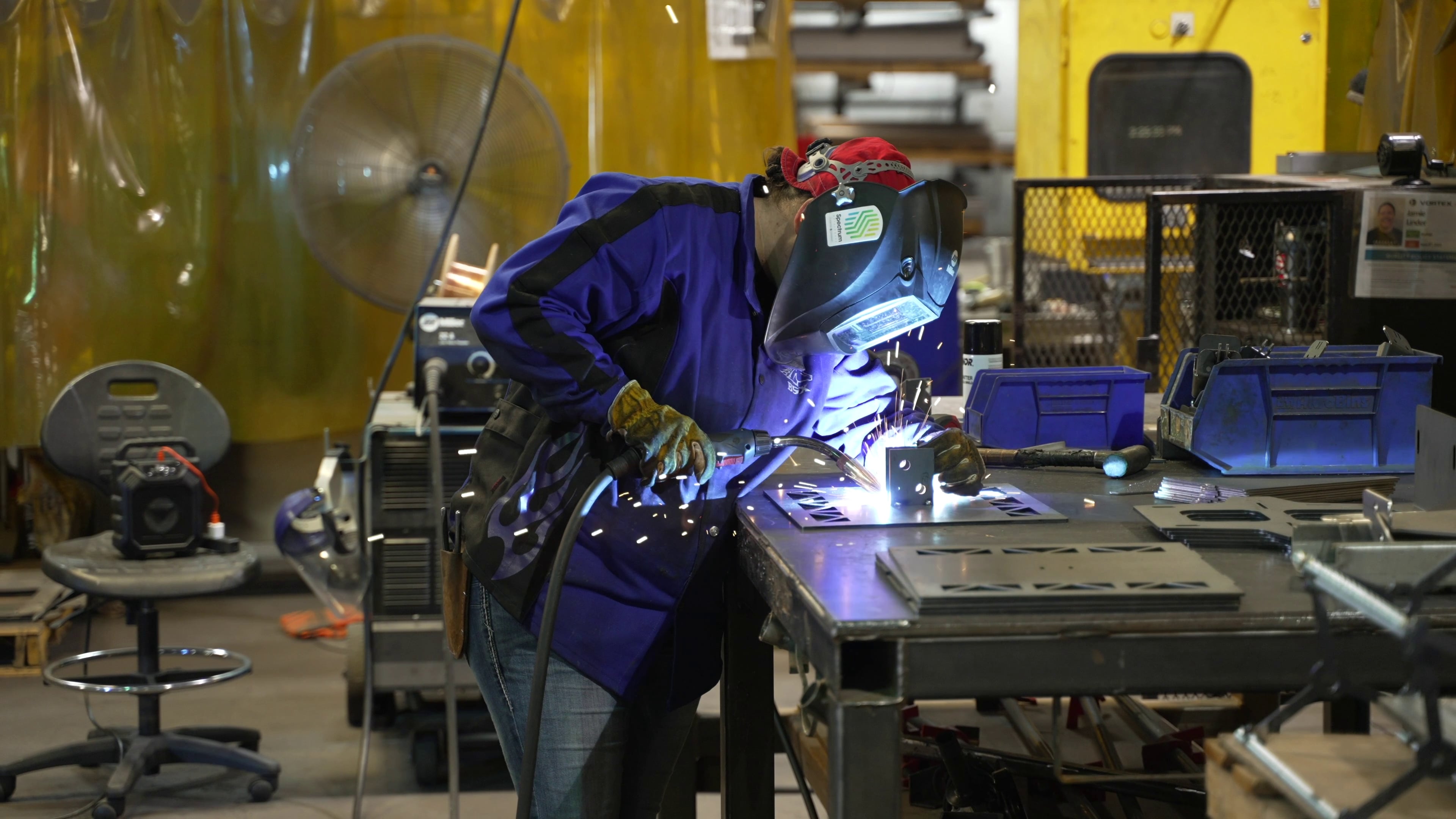 A welder welding a part at a company also using welding cobots
